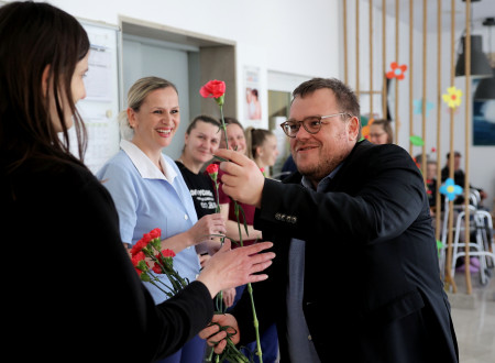 Minister ima v roki rožo, ki jo daje zaposleni v domu