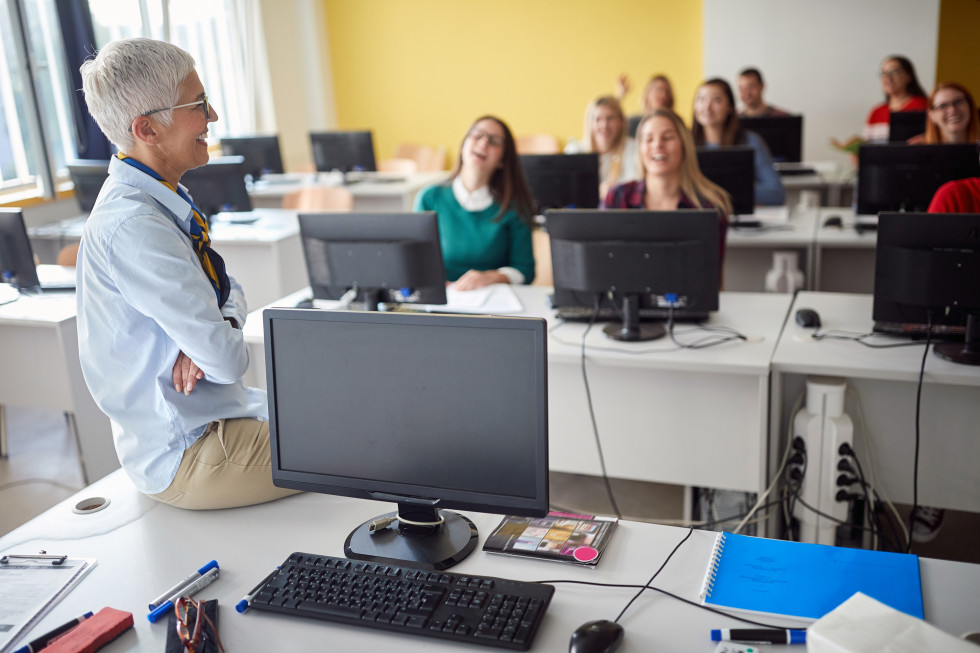 Udeleženke usposabljanja v predavalnici sedijo za računalniki.