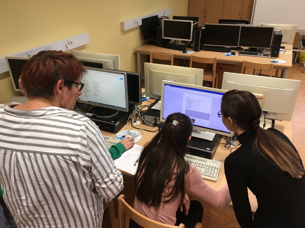 Deklice z učiteljico uporabljajo računalnik.