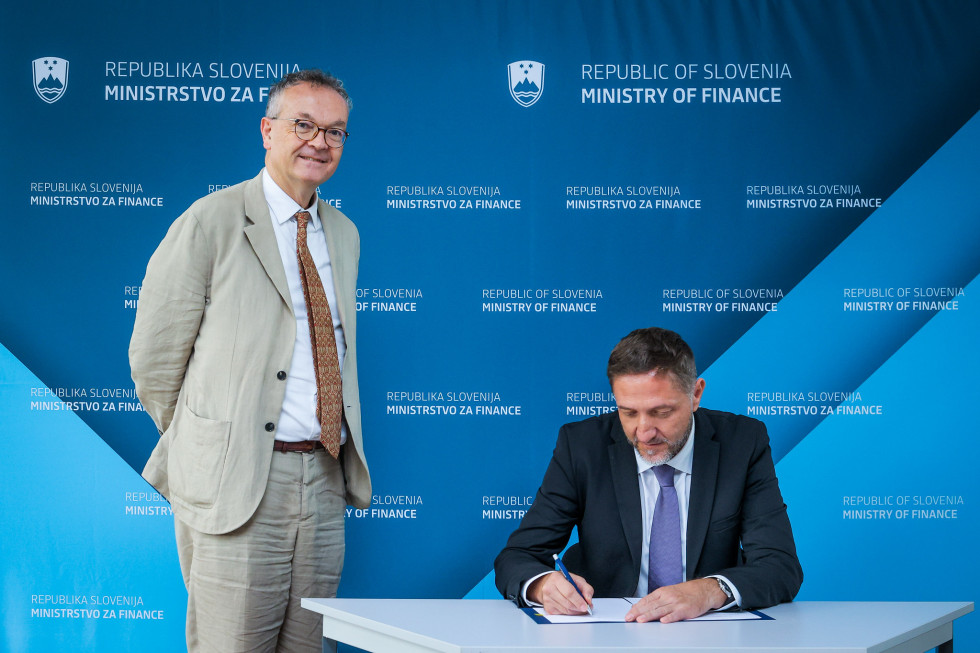Minister Boštjančič podpisuje sporazum, ob njem stoji direktor Bruegla