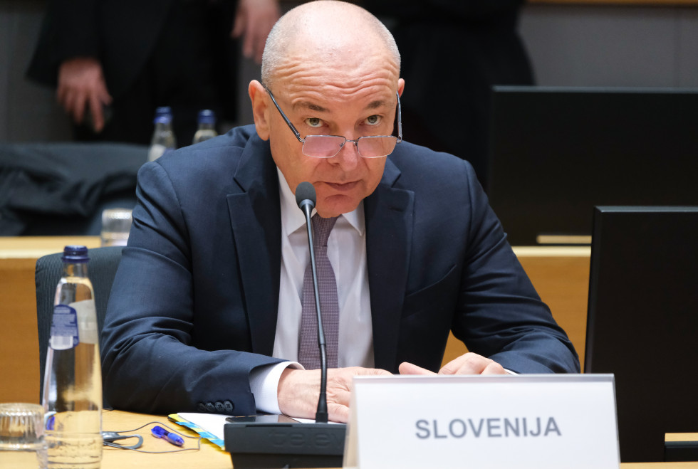 Minister sedi za mizo, pred njim je tablica z napisom Slovenija