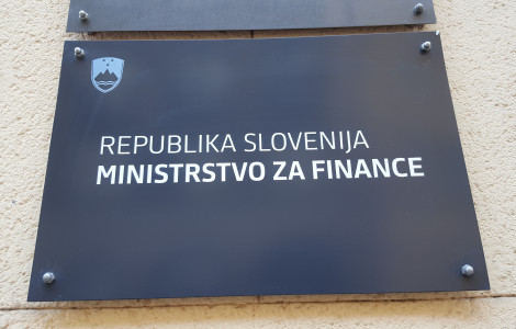 MF stavba 2 (Napisna tabla Ministrstva za finance. Temna podlaga, na njej bel napis Republika Slovenija, Ministrstvo za finance. Levo zgoraj nad napisom grb Republike Slovenije. )