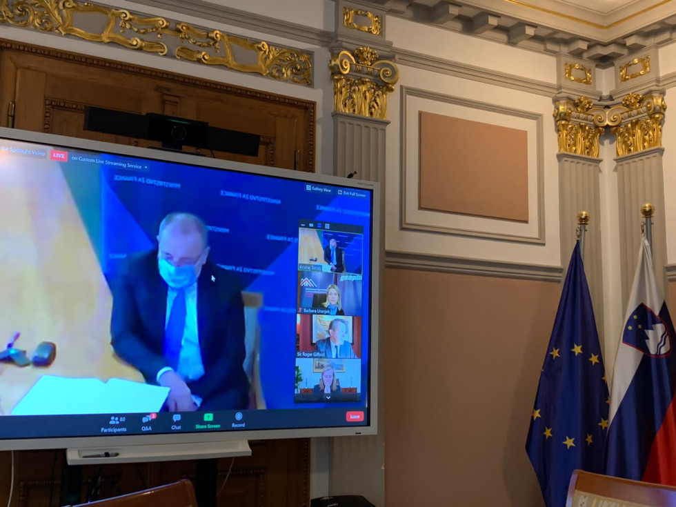 Videokonferenca, minister Šircelj nagovarja udeležence dogodka, na ekrani minister in udeleženci v manjših okencih. 