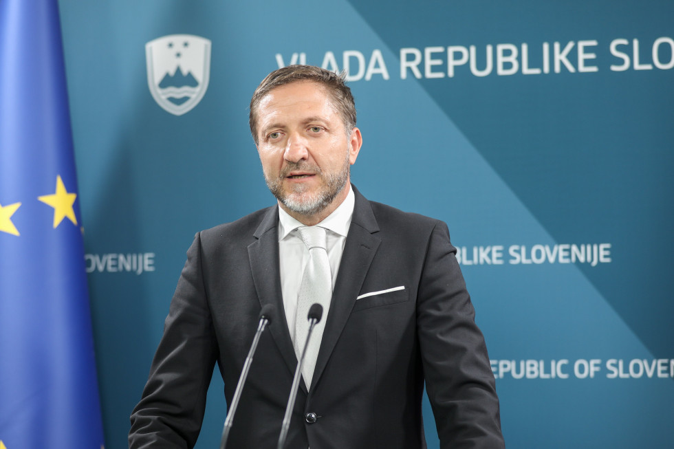 Minister Klemen Boštjančič za govorniškim pultom v novinarskem središču vlade.