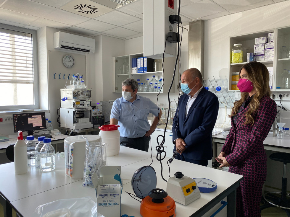 Minister Šircelj, poslanka Eva Irgl in direktor podjetja BIA Separations v laboratoriju. Na pultu pred njimi veliko laboratorijske opreme. 