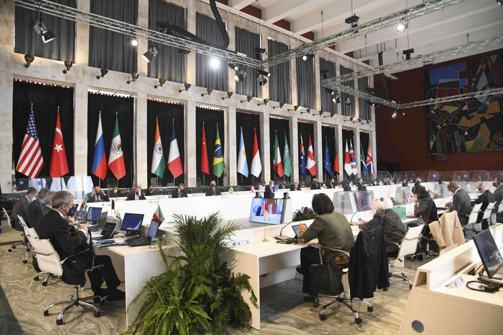 Ministri sedijo za mizo, v prostoru so na drogovih obešene zastave sodelujočih držav