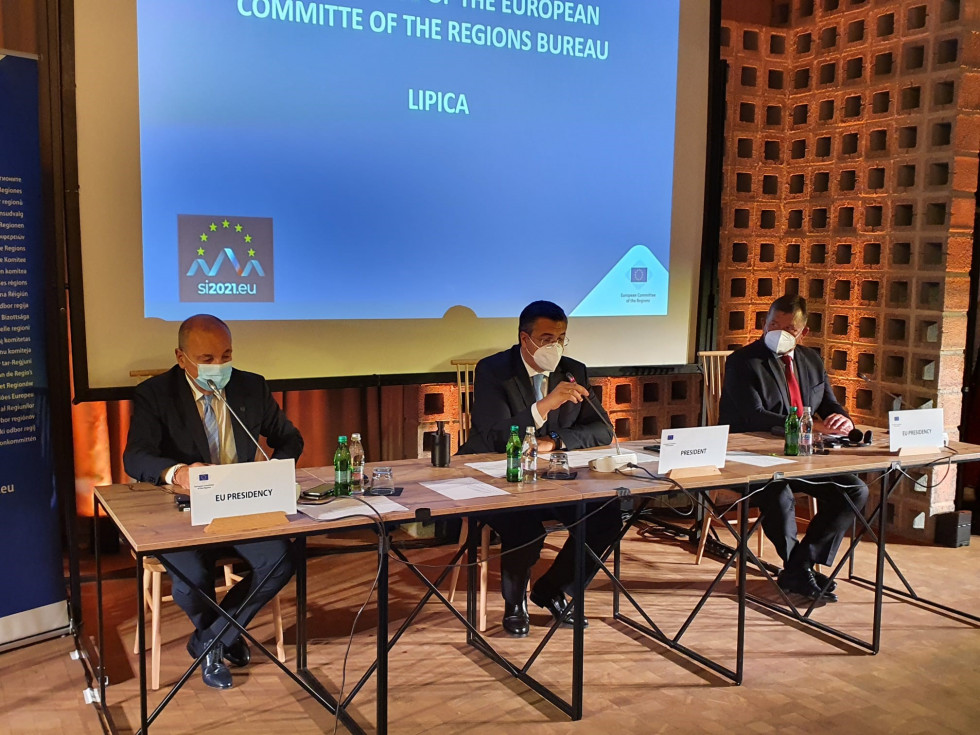 minister Šircelj, predsednik Evropskega odbora regij in še en govorec sedijo za mizo z mikrofoni, za njimi je pano z imenom dogodka