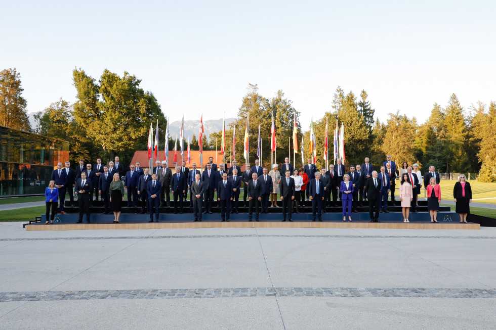 Skupinska fotografija ministrov za finance držav članic EU. V ozadju zastave držav članic EU, posamezne krošnje dreves in Kamniško-Savinjske alpe.