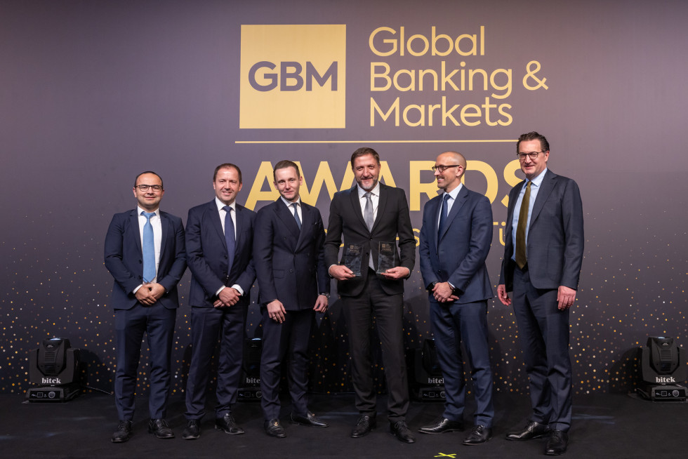 Slika ministra Boštjančiča  z obema nagradama v rokahna odru s podelitelji nagrad.