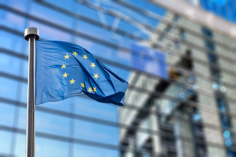 Zastava plapola v zraku, v ozadju se vidi poslopje ene od institucij EU
