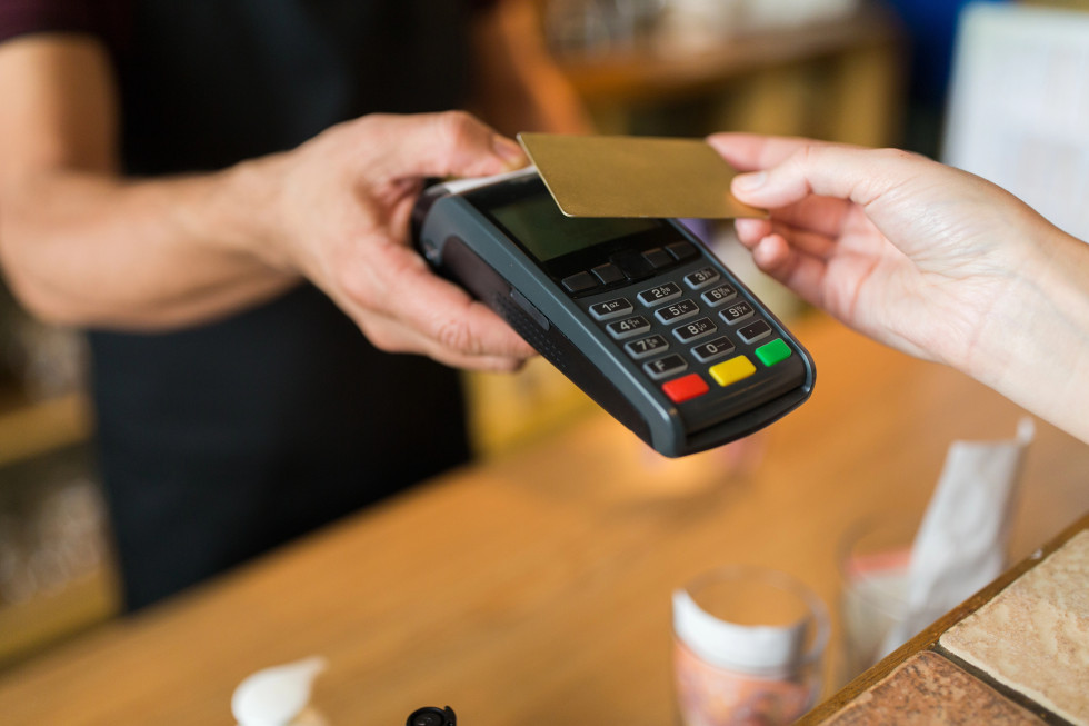 Hands with payment terminal and credit card.