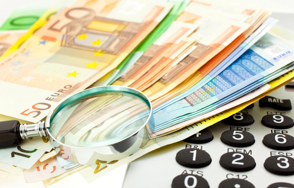 Bankovci za 50, 100 in 20 evrov, povečevalno steklo in kalkulator.