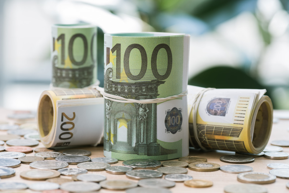 Na mizi ležijo evrski kovanci in bankovci za 100 in 200 evrov