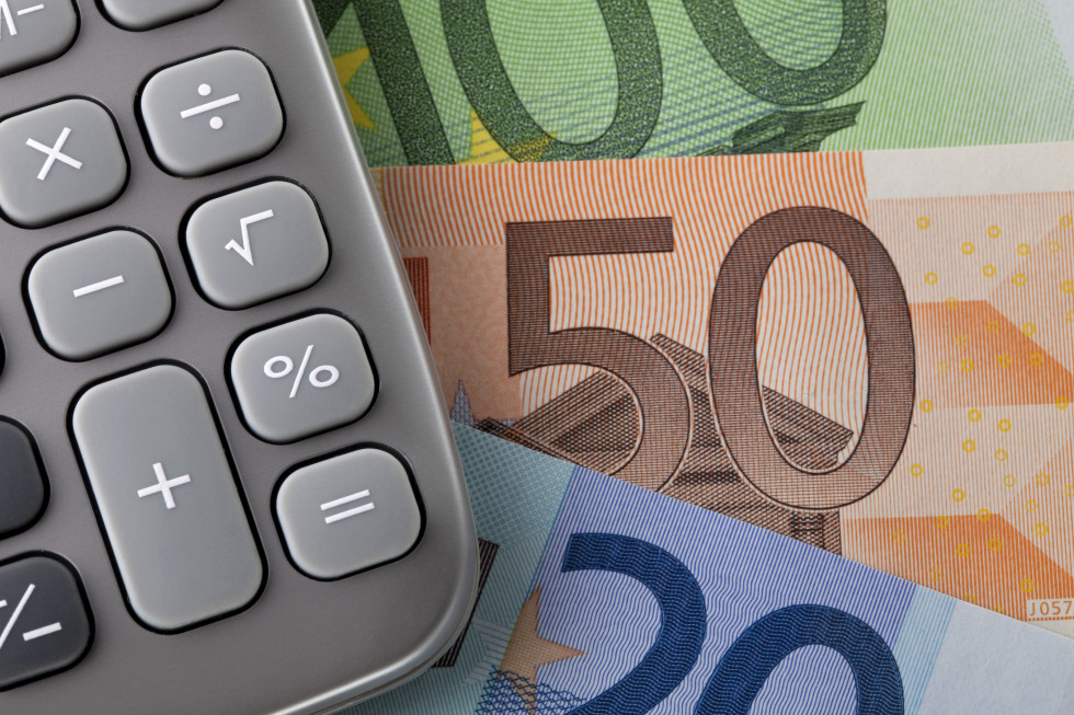 Lower right corner of the gray calculator, below it euro banknotes for 20, 50 and 100 euros.