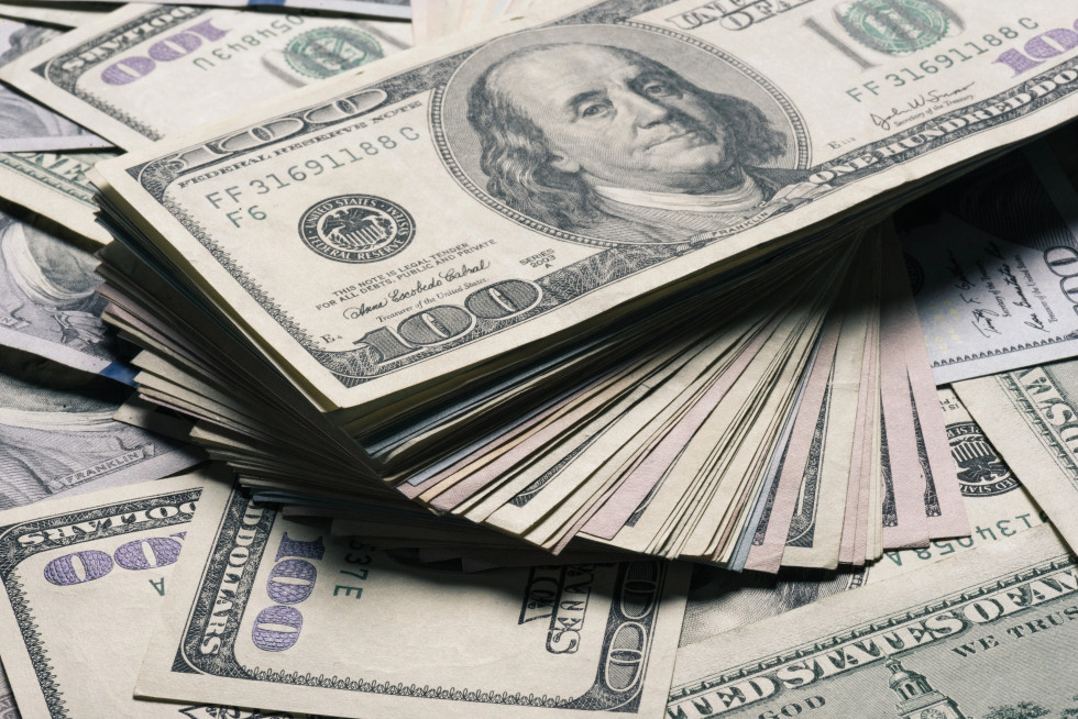 One-hundred-dollar notes spread out across the surface and stacked in a column.