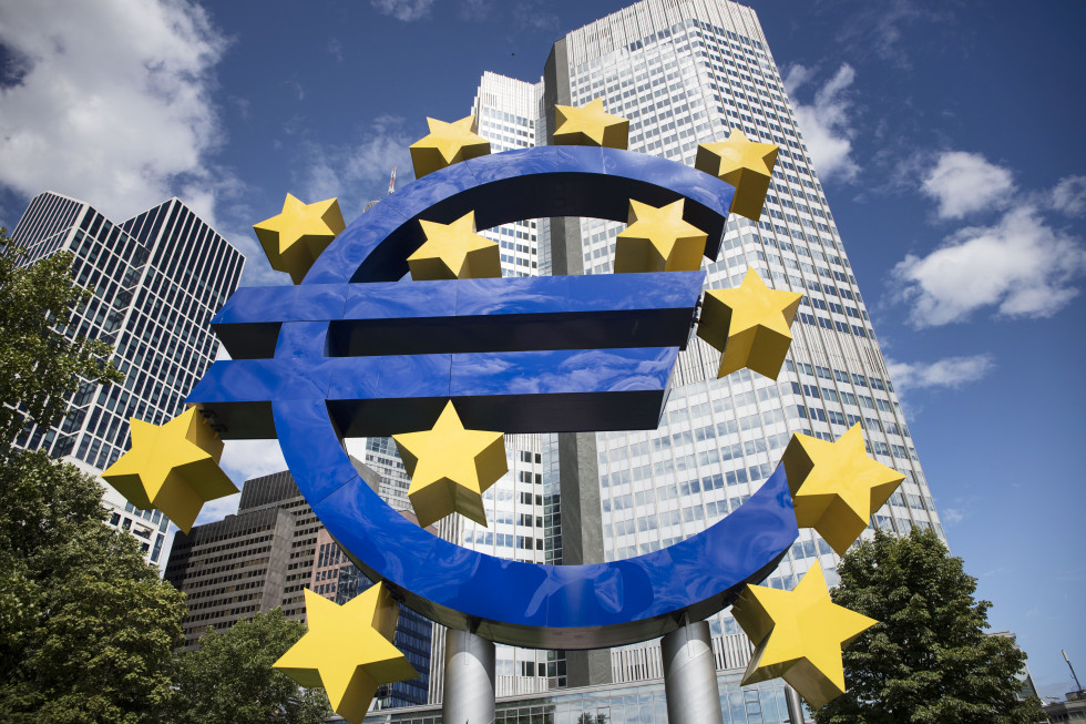 Moder znak za evro z rumenimi zvezdicami, v ozadju je poslopje Evropske centralne banke