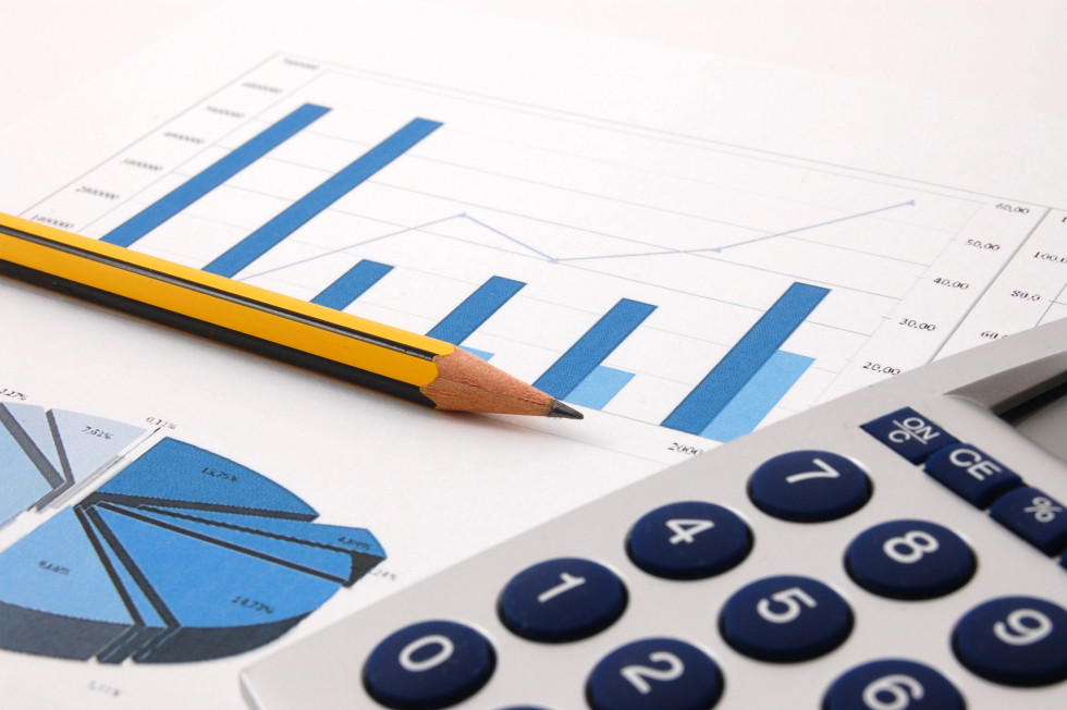 A sheet of paper with two graphs on it is lying on a table, with a pencil and a calculator on top of it.