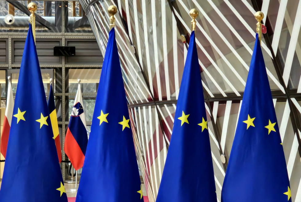 V ospredju so štiri zastave Evropske unije, v ozadju pa je zastava Slovenije