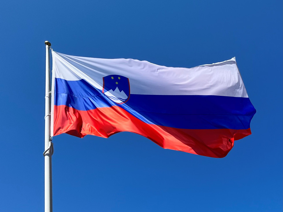 The Slovenian flag flutters in the wind as it flies from a pole