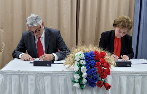 IMG 9b56d631401dedd2e13e74aebd3c169e V (Two individuals signing a contract at the table with flowers)