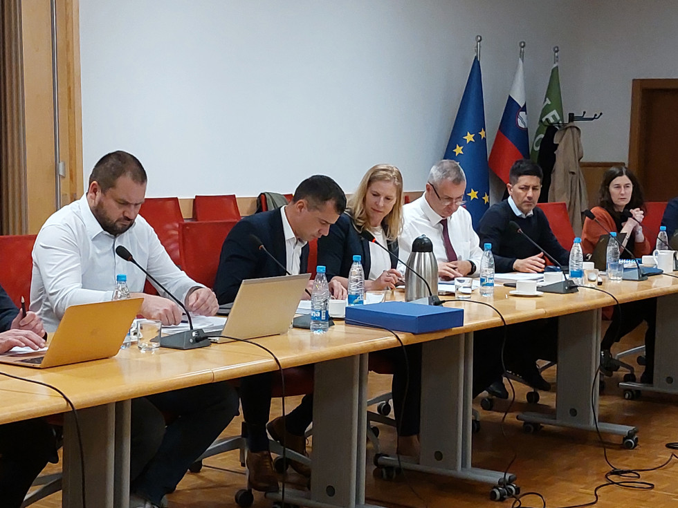 člani sveta za omizjem, v ozadju zastave