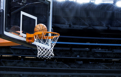 Depositphotos 40387999 yobro10 (Basketball goes through the orange hoop and net attached to a backboard in an indoor arena with bright lights.)