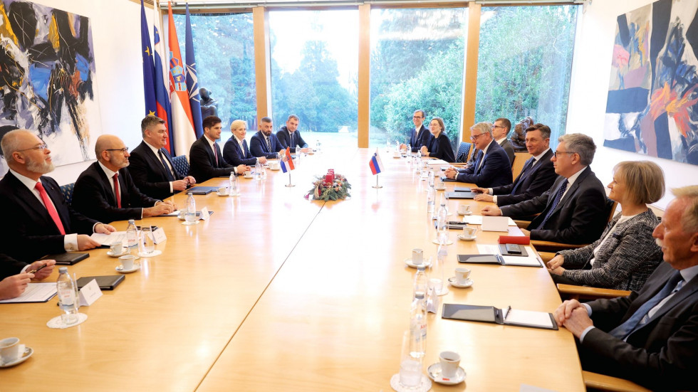 delegaciji za dolgo leseno mizo - na levi strani hrvaška, na desni pa slovenska delegacija