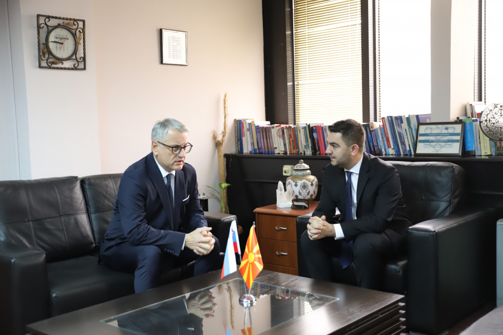 Minister Han in makedonski minister sedita za klubsko mizo, pred njima slovenska in makedonska zastava