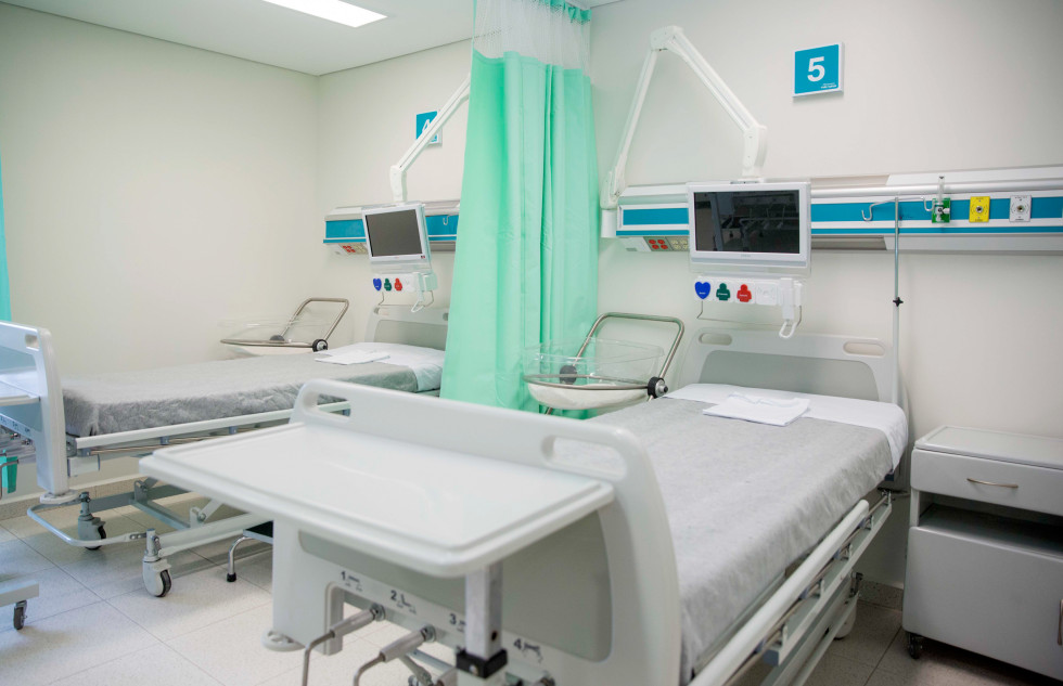 Bolniška soba s posteljami, aparaturami in predelno zaveso