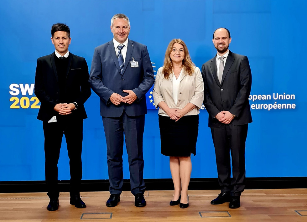 Four people in front of a blue official photo wall