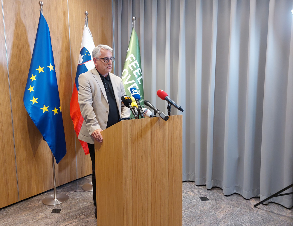 minister Han za govorniškim pultom na katerem so mikrofoni