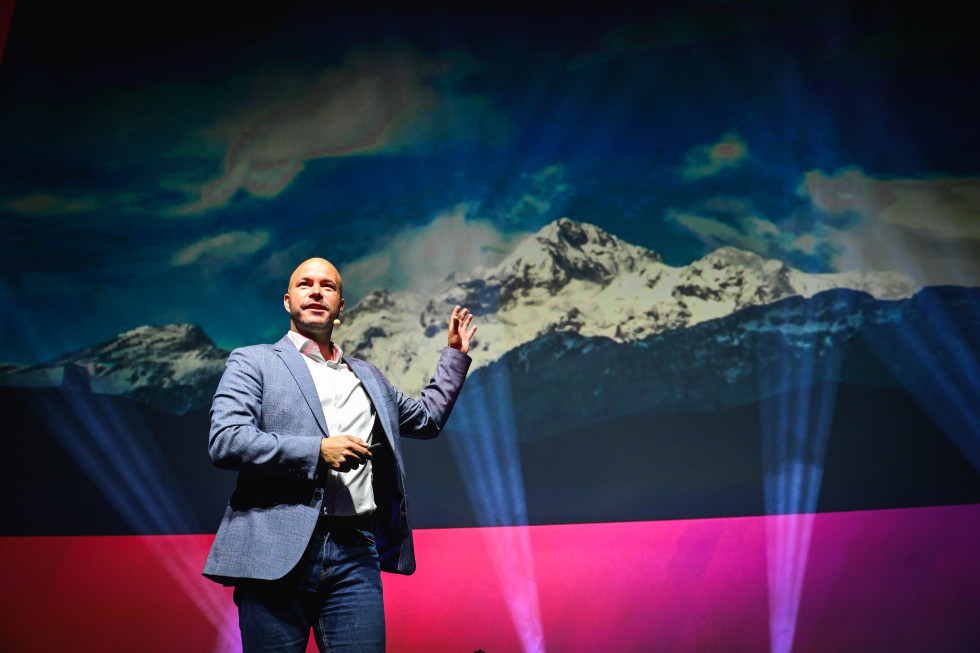Frangež on stage, a photo of Triglav in the background