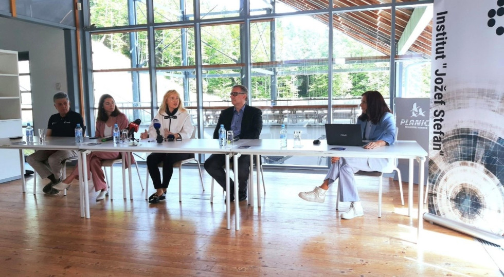 govorci za mizo, ob strani pano Instituta jožef Štefan