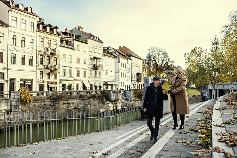 Starejša gospa in gospod se sprehajata po centru Ljubljane