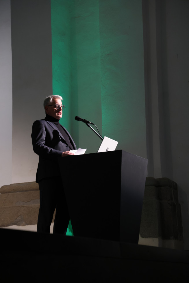 Moški stoji za govorniškim pultom.