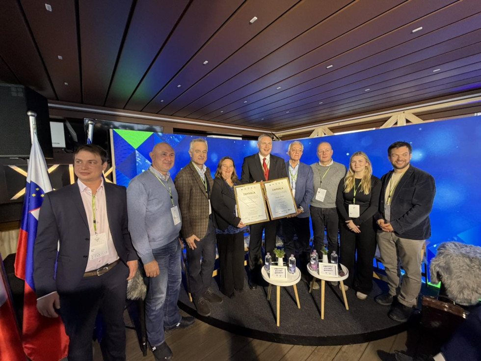 Moški in ženski stojijo eden zraven drugega. V rokah imajo zahvalo.