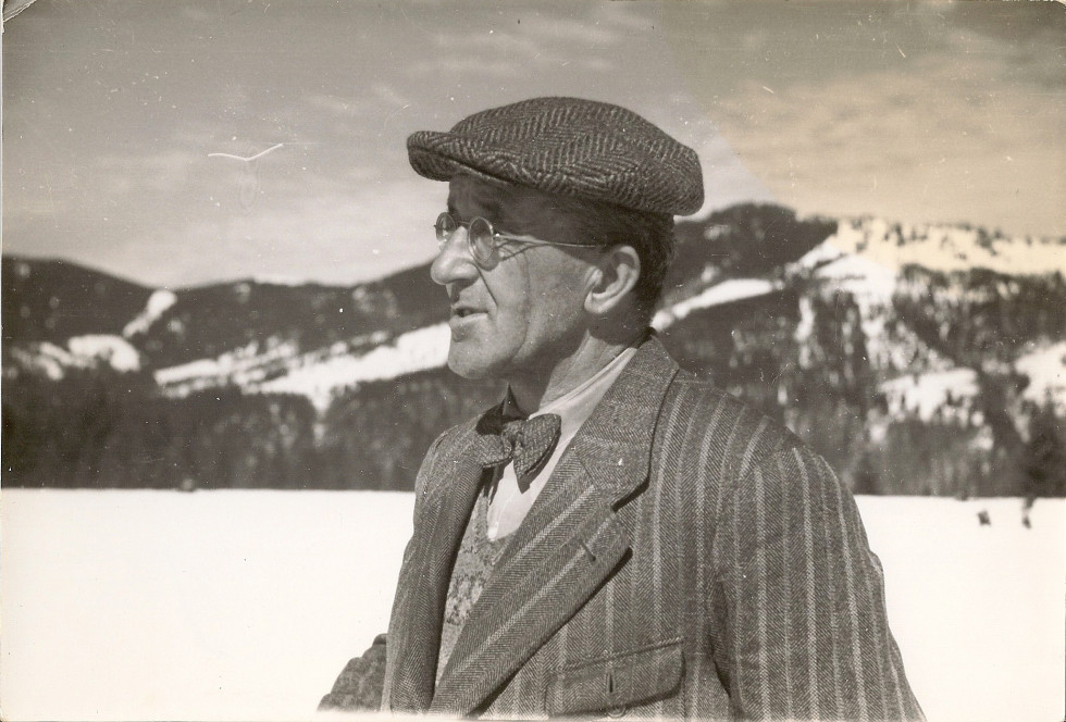 V ospredju je doprsna slika Stanko BloudekSlika stranka Bloudka iz njegovega levega profila, v ozadju zasnežena pokrajina 