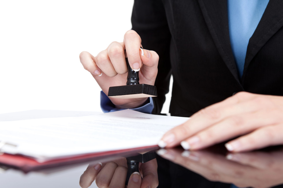 ženske roke v obleki žigosajo dokumente