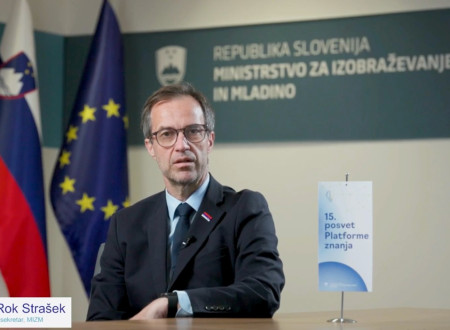 Državni sekretar dr. Rok Strašek v prostorih ministrstva. V ozadju sta slovenska in evropska zastava ter znak 15. posveta Platforme znanja.
