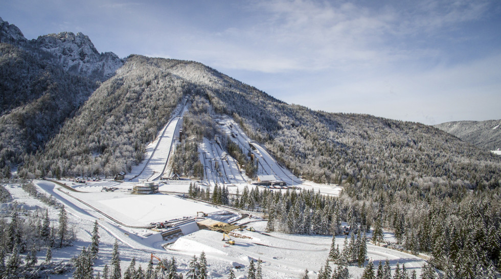 Na sliki je Nordijski center Planica pozimi. Vidne so vse skakalnice in okoliški hribi.
