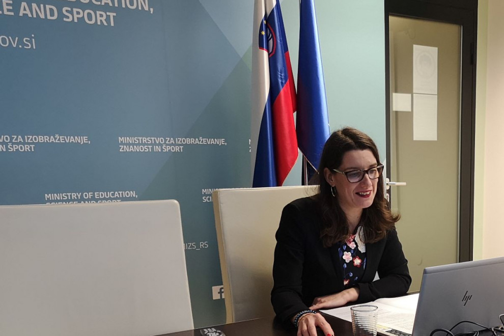Ministrica prof. dr. Kustec v pisarni za računalnikom sodeluje na video konferenci. 
