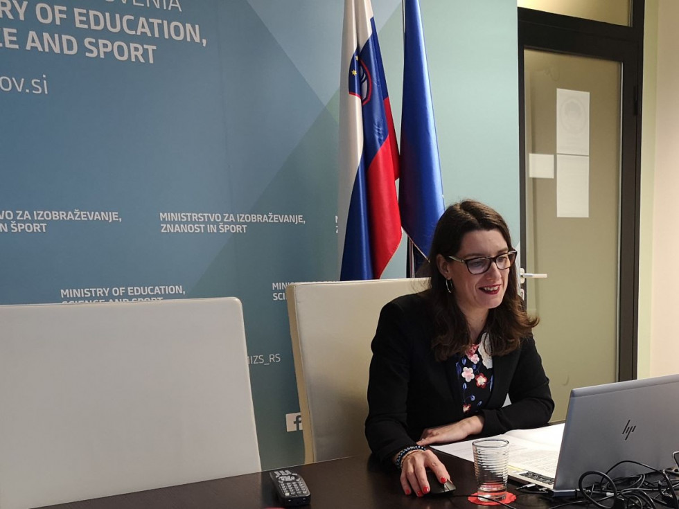 Ministrica prof. dr. Kustec v pisarni za računalnikom sodeluje na video konferenci. 