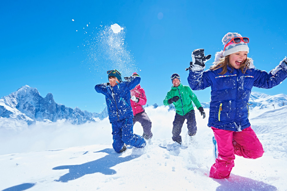 Skupina otrok med igro na snegu.