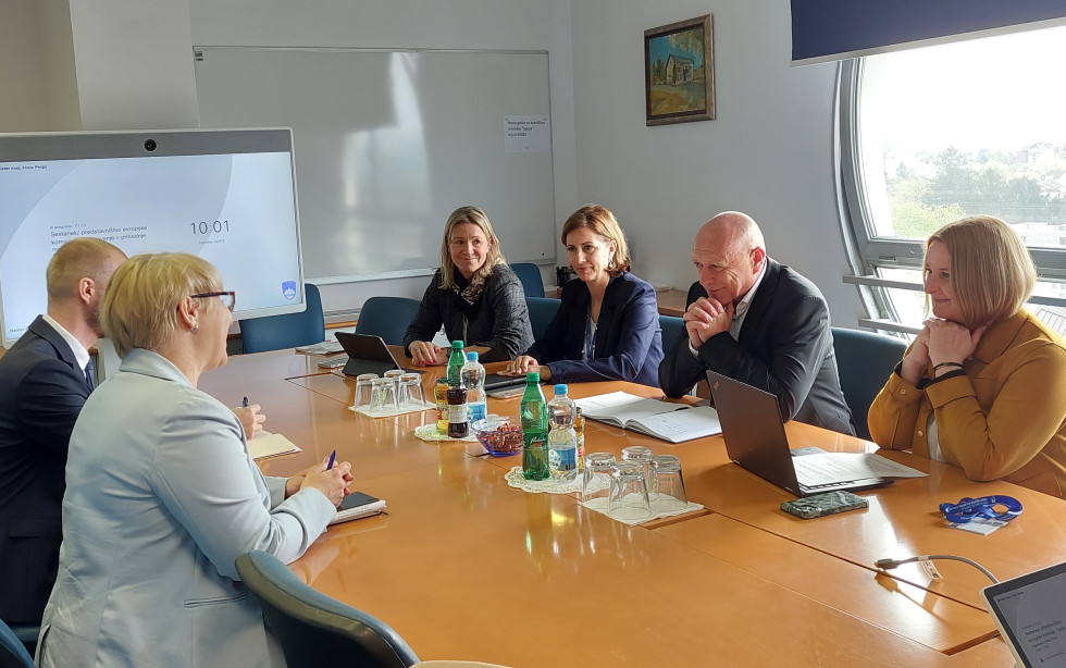 Minister s sodelavkami sedi za mizo v sejni sobi in izraža dobrodošlico ob spoznavnem srečanju z dr. Jernejo Jug Jerše 