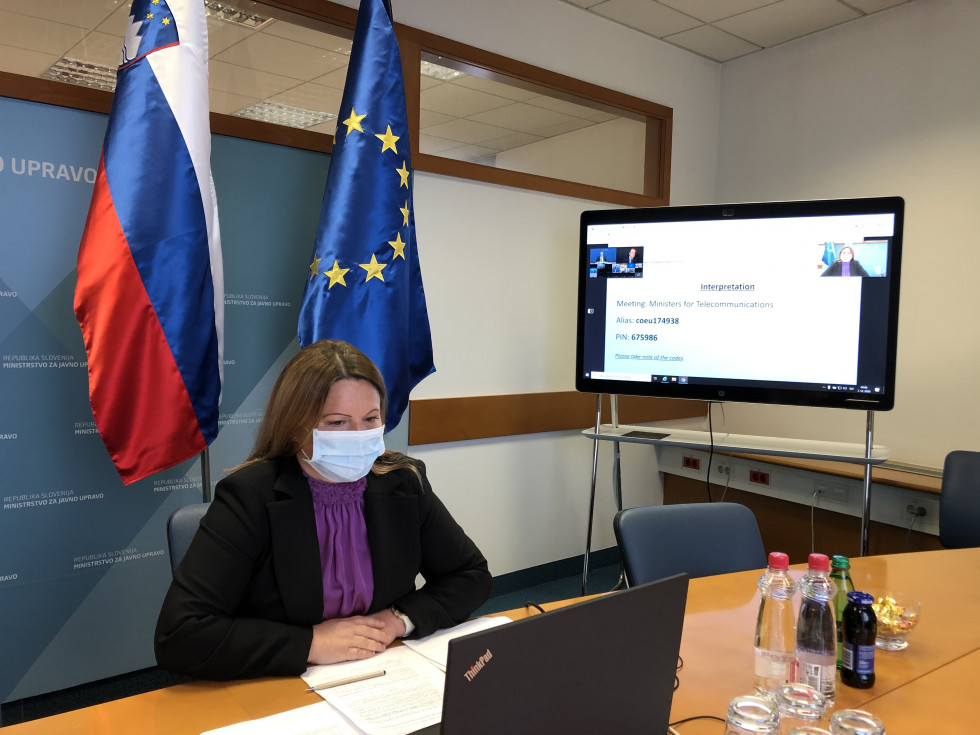 Državna sekretarka Urška Ban sedi za mizo pred računalnikom