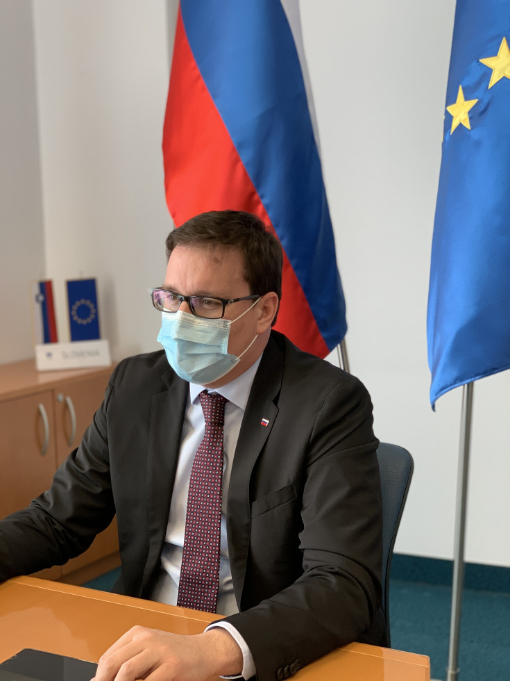 Minister sitting with flags behind him