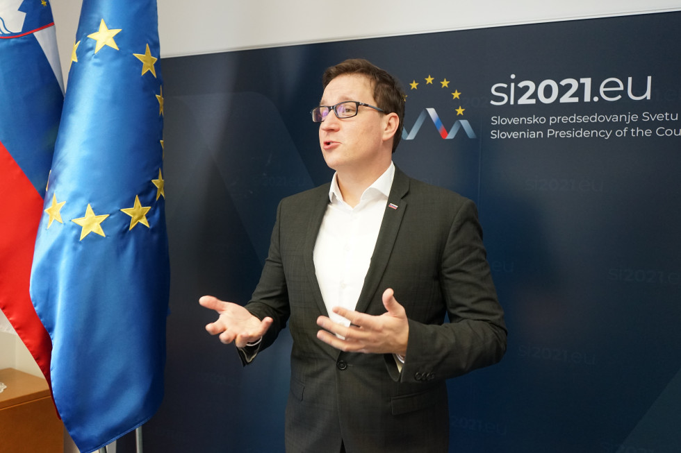 minister stoji pred ozadjem z logotipom slovenskega predsedovanja