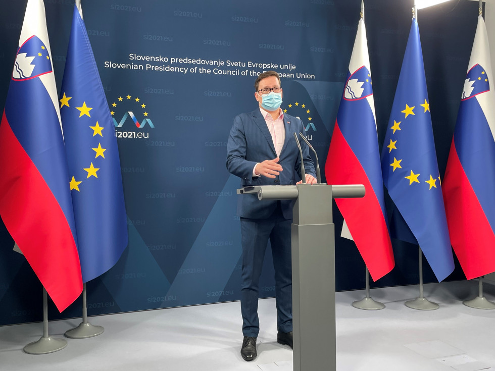 Minister Koritnik stoji za govornico, za njim ozadje predsedovanja, od straneh zastave Slovenije in EU