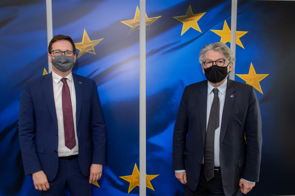minister in komisar stojita pred panelom z evropsko zastavo