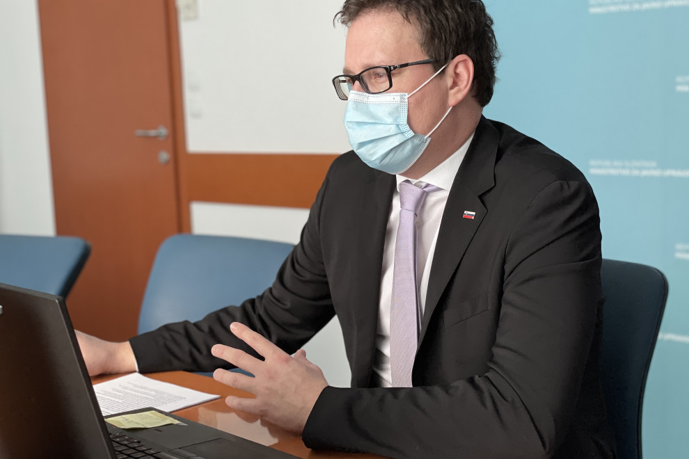 minister sedi pred računalnikom med nagovorom prek videopovezave